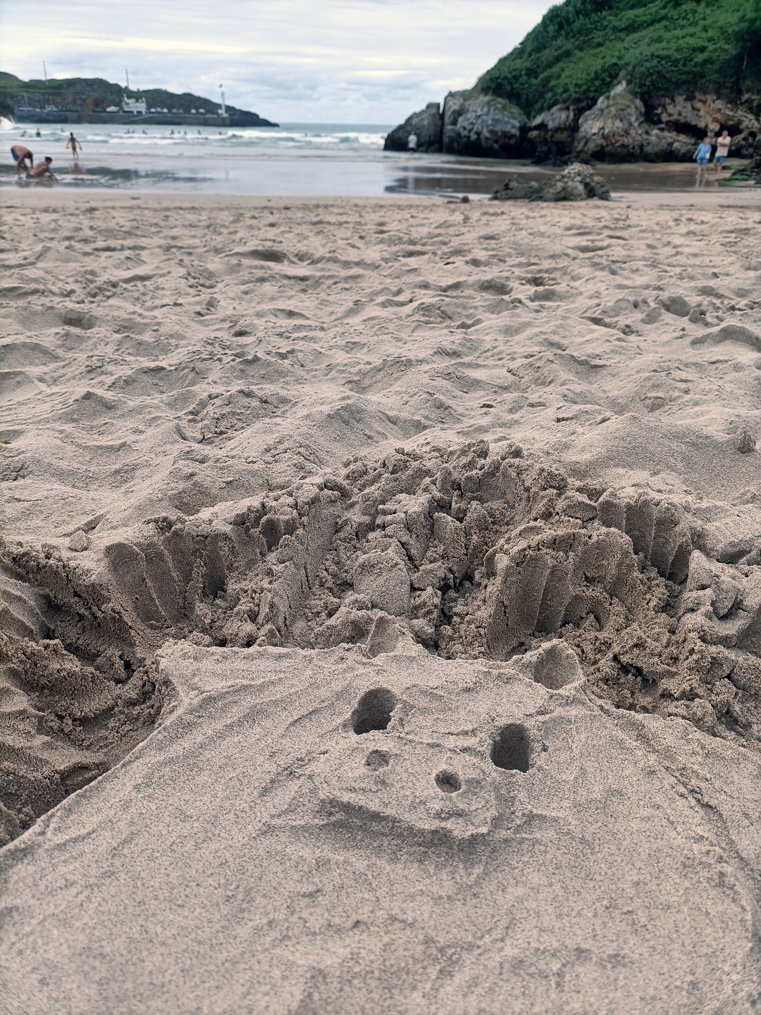Un cerdílope esculpido en la arena de una playa con el mar al fondo