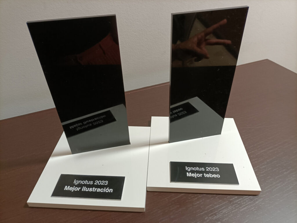 Foto de dos premios Ignotus sobre una mesa, el de tebeo y el de ilustración, ambos de 2023