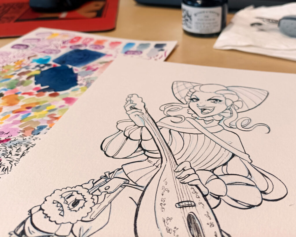 Foto de una mesa con un bote de tinta, un papel de pruebas de acuarela y un dibujo recién entintado de una Liliidae con un Jacin Labubu colgando del cinturón.